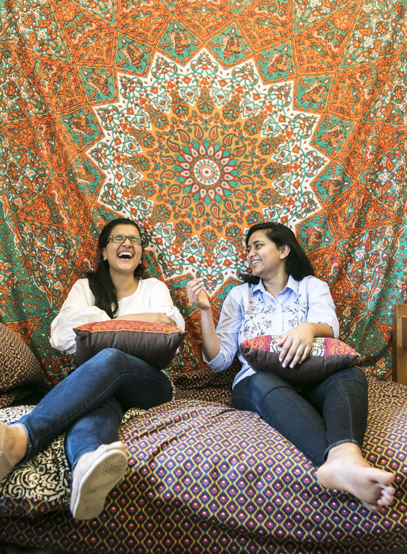 Two female college student roommates relax and laugh together during time in their dorm room in a photo by Ryan Donnell