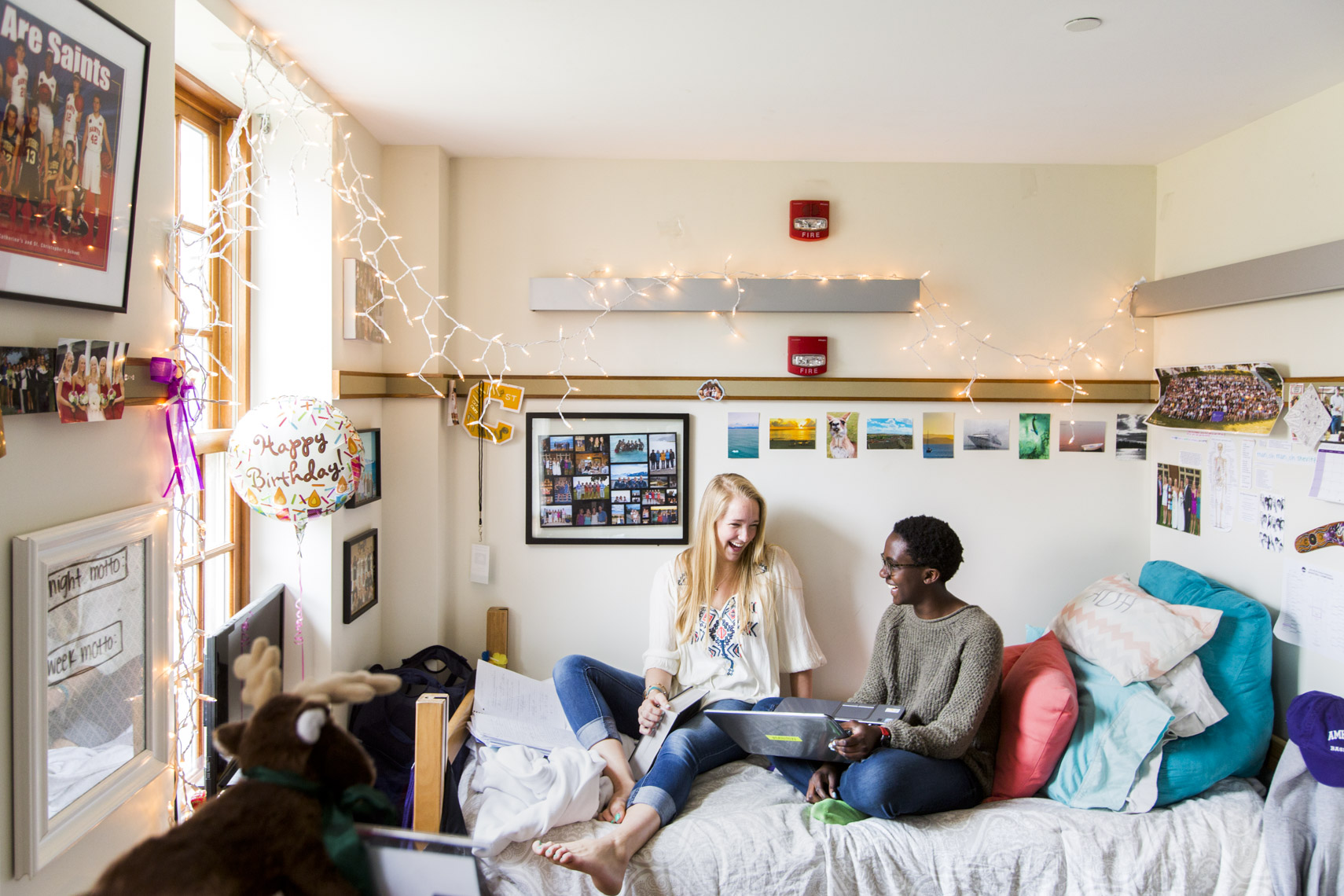 Two female college students laugh in their dorm room in a photo by Ryan Donnell
