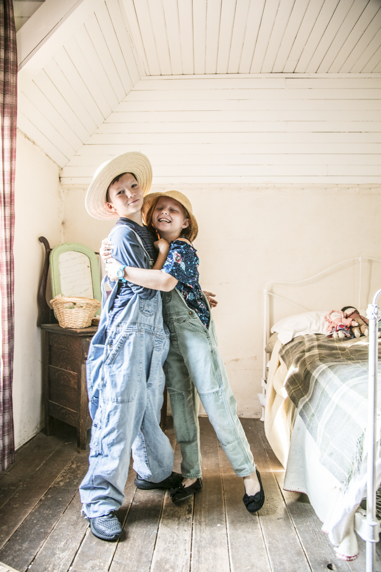 A portrait of a brother and sister in overalls hugging each other  by Washington DC photographer Ryan Donnell