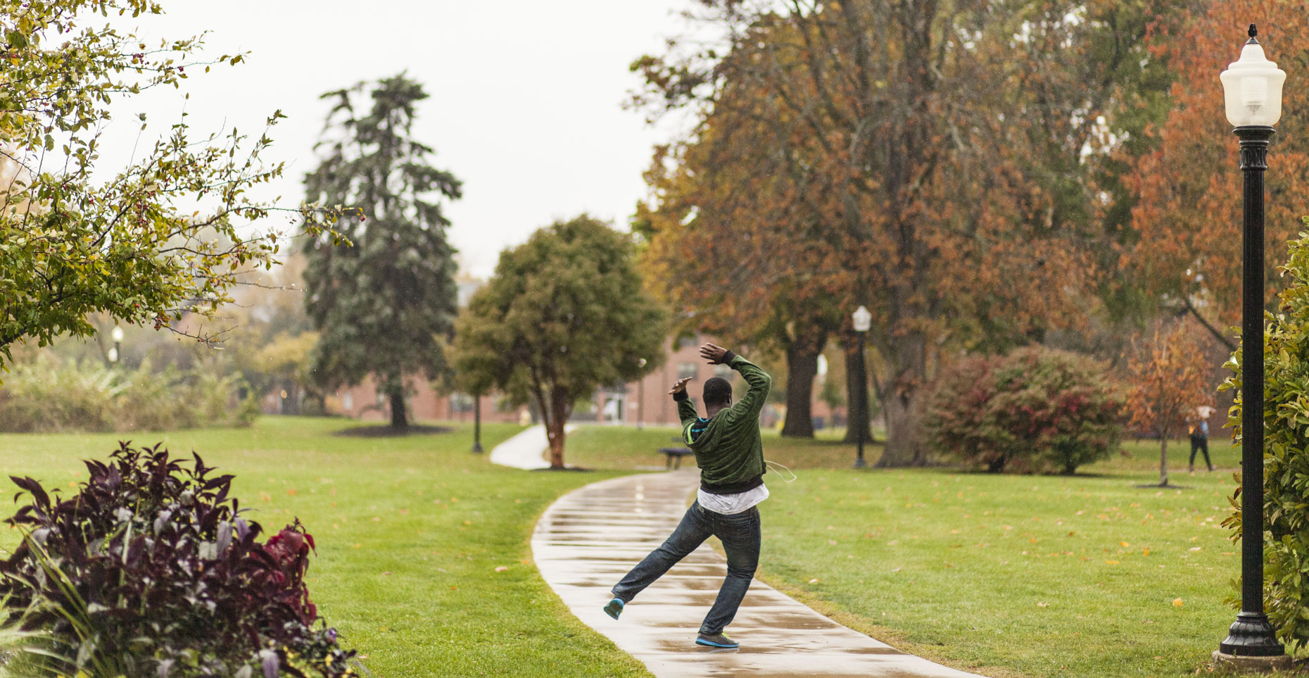 A college student dances in a sudden rain shower on campus in a photo by Ryan Donnell