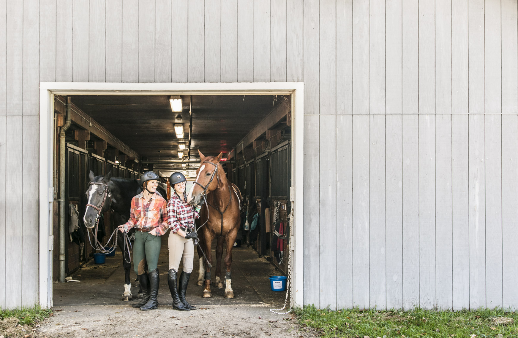 A portrait of two college equestrian athletes at the horse stables in a photo by Ryan Donnell