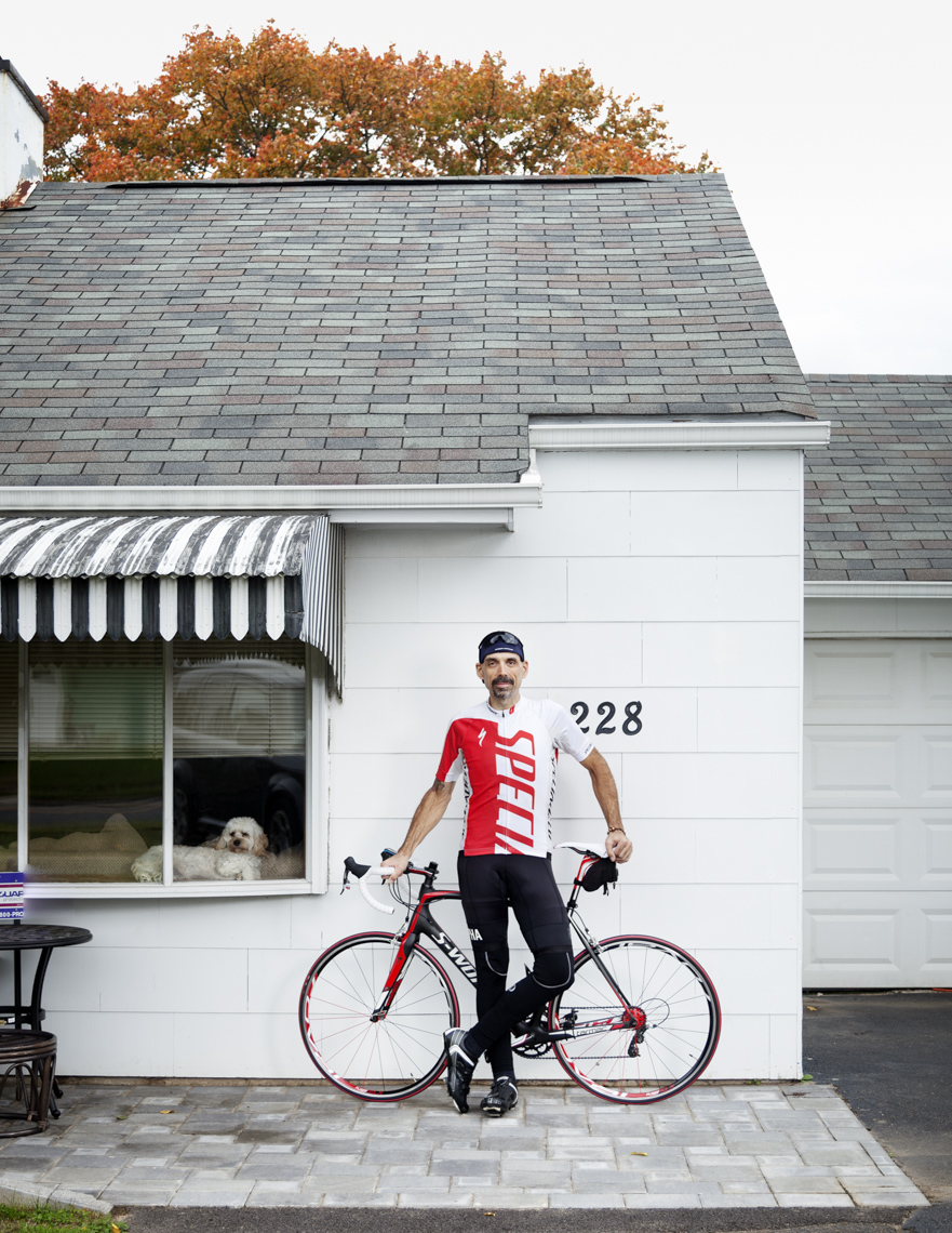 Editorial portrait of a cyclist standing in front of his house  by Washington DC photographer Ryan Donnell