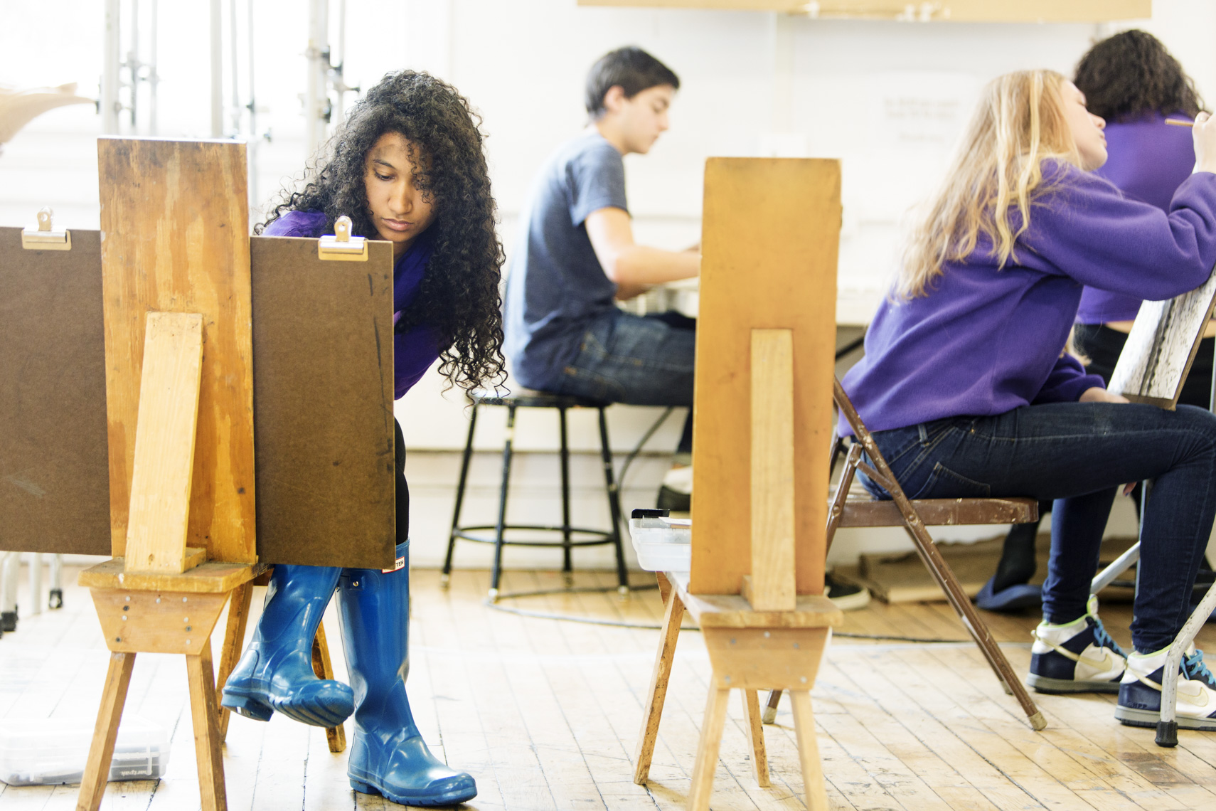 A female student works on an art project with other students  in a college class in a photo by Ryan Donnell