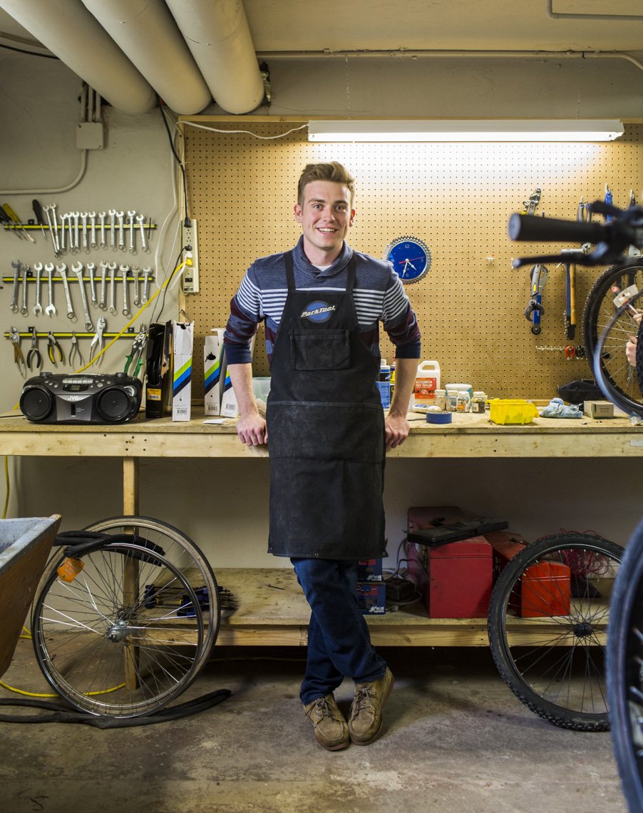 A full-length portrait of a student worker at a campus-run bicycle repair shop by Ryan Donnell