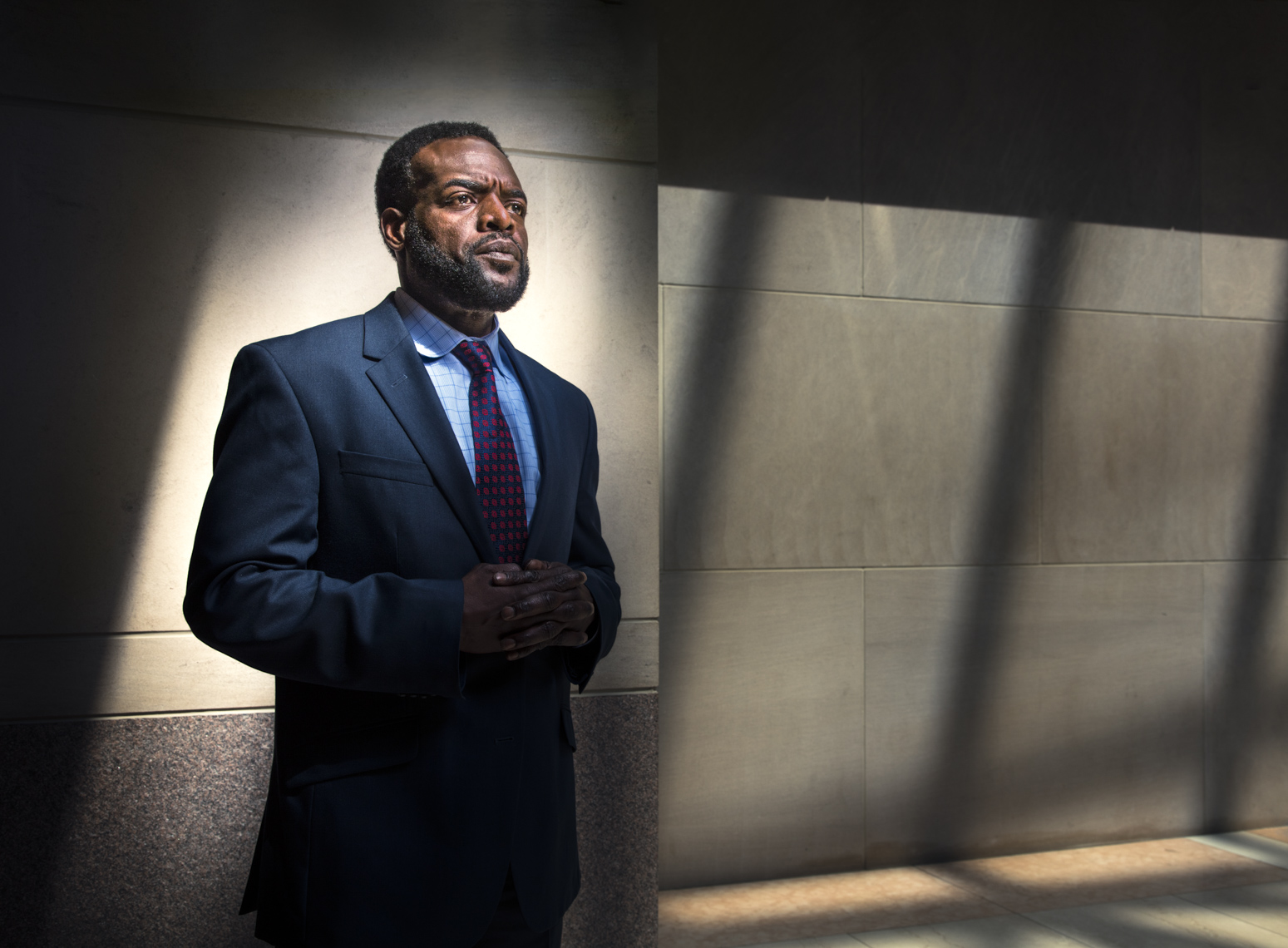 Portrait of a man in a business suit surrounded by shadows  by Washington DC photographer Ryan Donnell