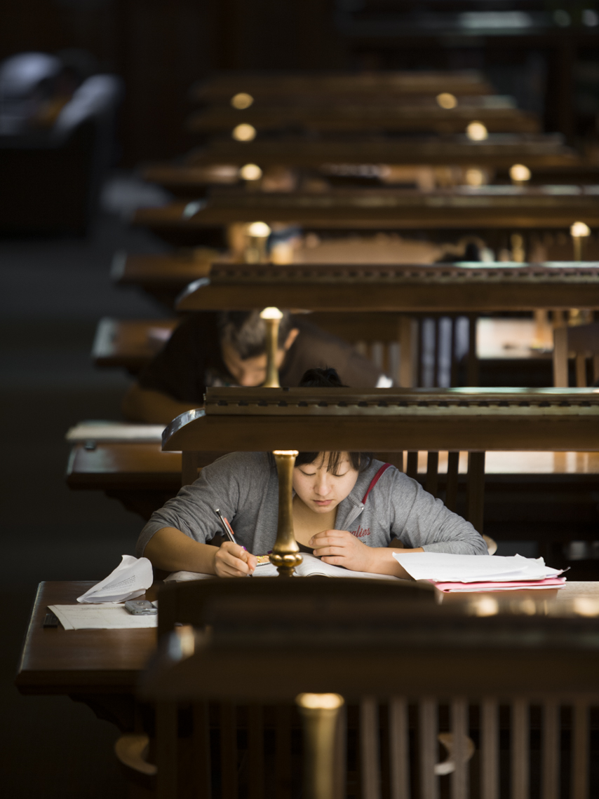 A university student studies in a campus library under soft lamp light in a photo by Ryan Donnell