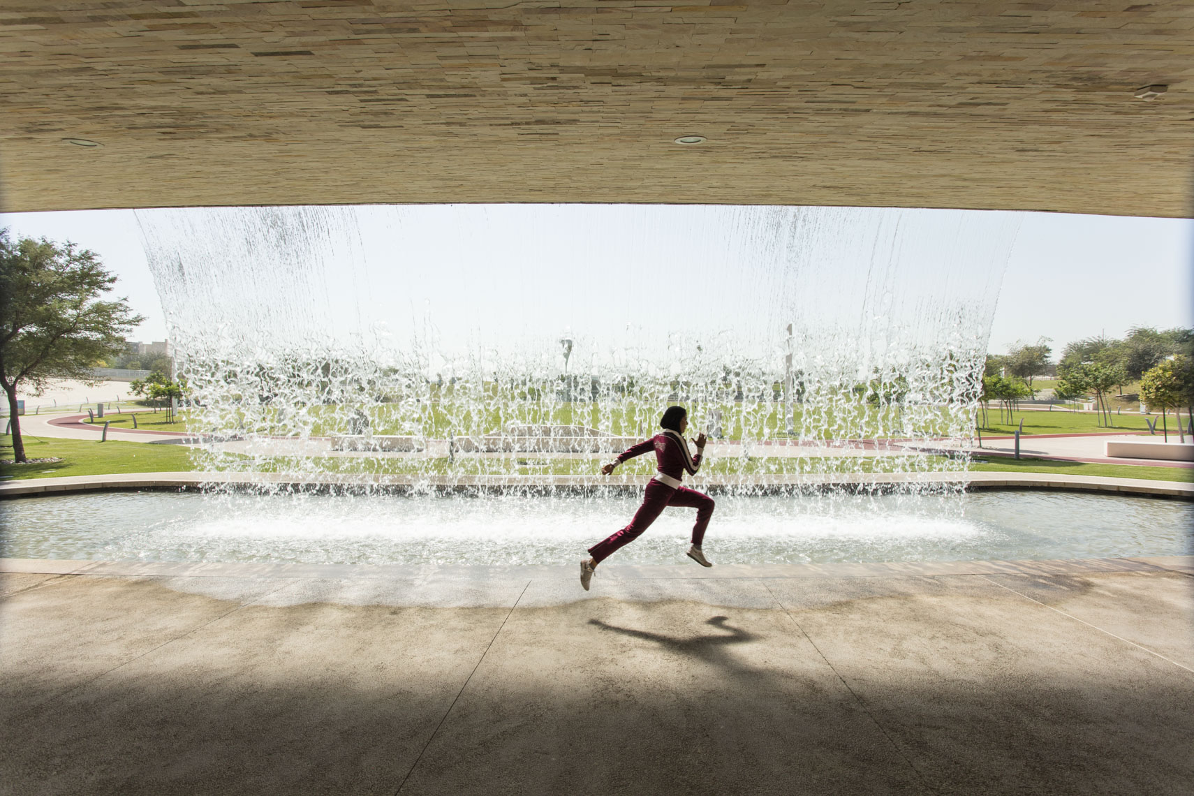 A muslim student athlete trains in front of a waterfall in Doha, Qatar in a photo by Ryan Donnell